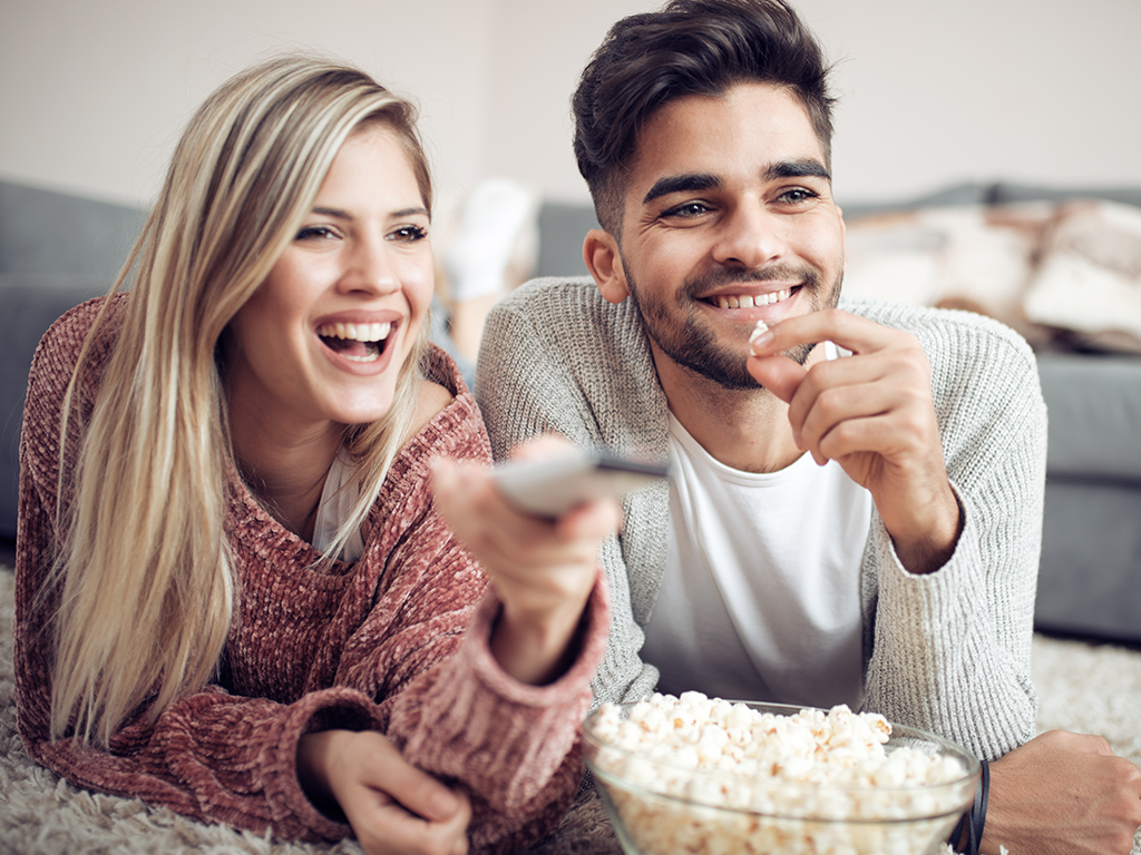 Couple eating popcorn while watching tv